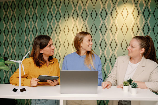 三位女商人在一间带着风力涡轮机模型的现代办公室里讨论可持续发展项目图片下载