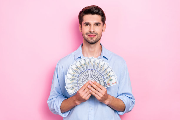 有魅力的富人穿着时尚的衣服，手拿钱的照片被隔离在粉红色的背景上图片下载