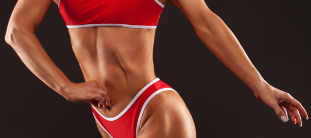 一个苗条黝黑的健美女孩，穿着白色背景的红色运动服。健康的生活方式，运动和饮食。图片下载