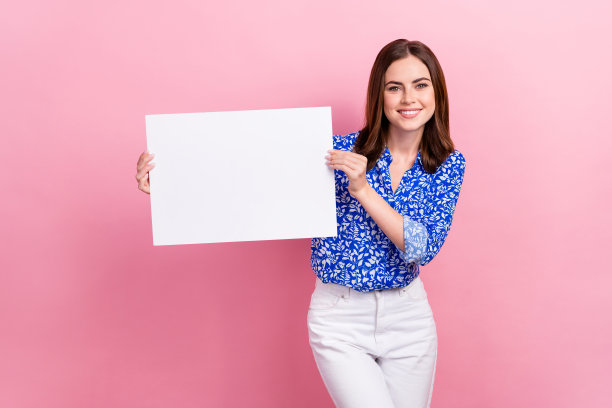 开朗积极的女士穿着正式的办公室装的照片拿着纸质海报宣传新品牌主张销售孤立在粉红色的背景图片下载