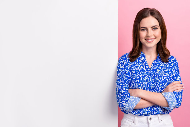 照片正面满意高兴开朗的女商人穿着蓝色衬衫交叉双臂靠近纸广告命题孤立在粉红色的背景图片下载