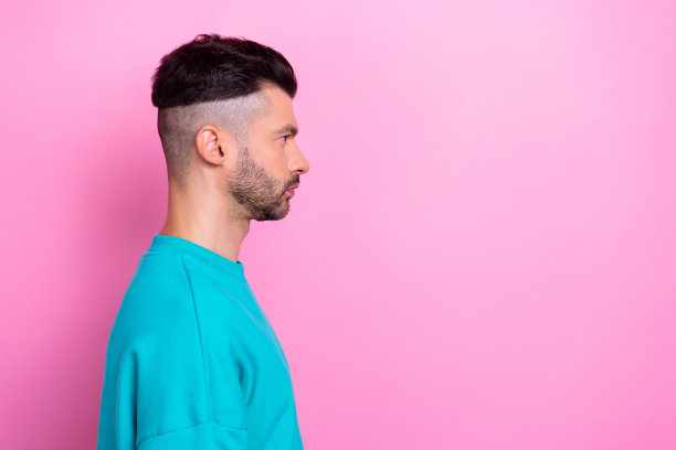 侧面侧面的照片，年轻的严肃自信的男子看起来空白后，理发店刚刚做了发型，孤立的粉红色背景图片下载