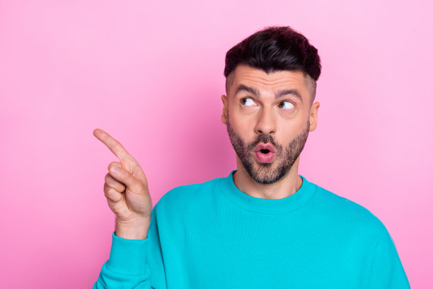 年轻惊奇的家伙的特写照片惊讶直接手指看着新奇的空白空间新的昂贵的餐厅菜单孤立的粉红色背景图片下载