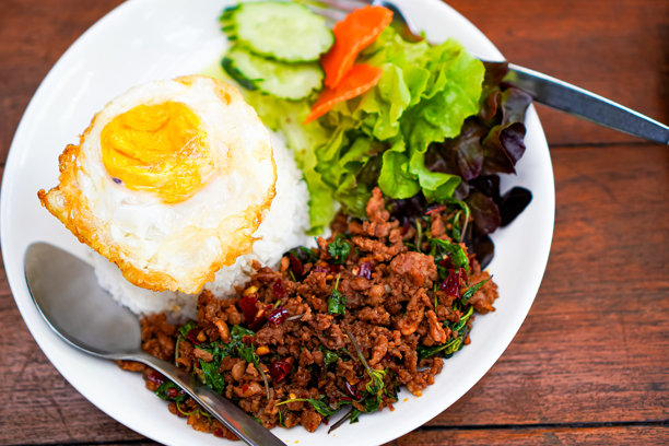 泰国清迈，木制餐桌上的泰式罗勒炒肉末和煎蛋的特写照片图片下载
