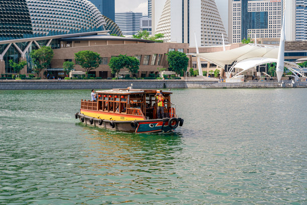 游船巡游在新加坡河与鱼尾狮和滨海湾天际线为背景。旅游的概念图片下载