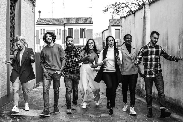 快乐的城市朋友们带着无忧无虑的心情在老城里疯狂地散步。这张照片捕捉到了充满活力的年轻人享受生活。黑白编辑。图片下载