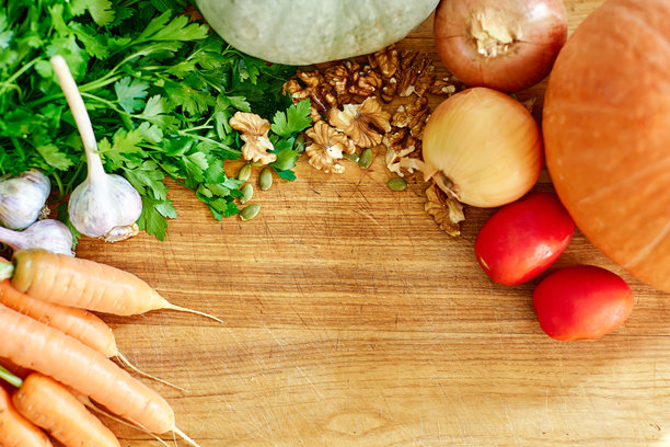 节日的秋天装饰南瓜，西红柿，绿色植物，坚果在木制背景。图片下载