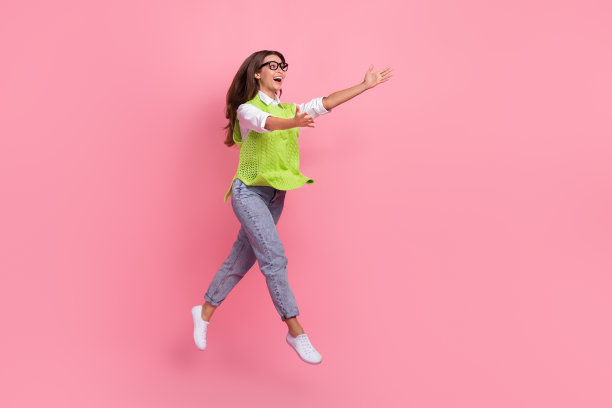 全尺寸照片，乐观开朗的好女人穿着绿色马甲牛仔裤鞋在销售孤立的粉红色背景图片下载