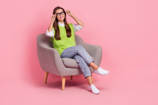 积极开朗的聪明女人的全尺寸照片马甲牛仔裤坐在扶手椅上看起来空旷的空间孤立在粉红色的背景图片下载