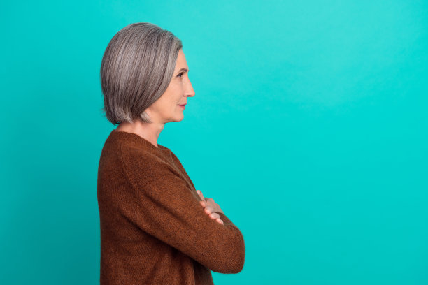 侧面照片华丽的女士穿着时髦的衣服，手臂交叉看起来很好，提供了青色背景上孤立的空白空间图片下载