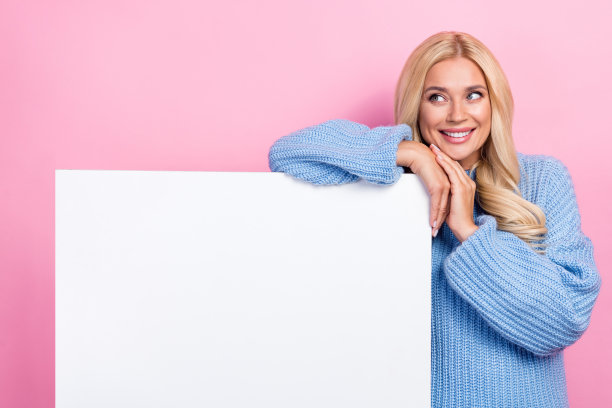 照片正面可爱的女士穿着时髦的蓝色套头衫，展示了空白的空间，有趣的提供孤立的粉红色背景图片下载