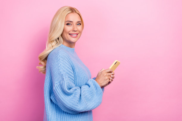 华丽时髦的女士手持现代设备的侧面照片建议购买优质的小工具，在粉红色的背景上留出空间图片下载