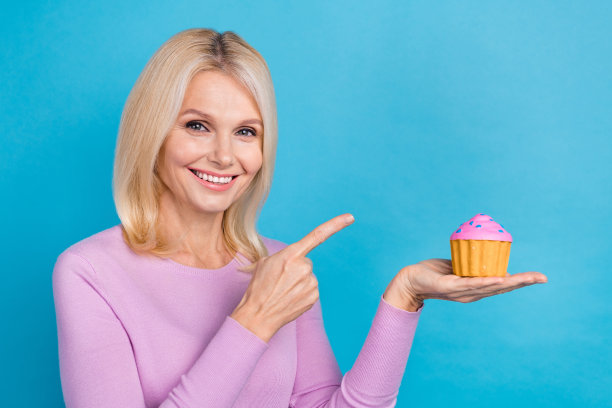 照片华丽的高兴时髦的女士掌心蛋糕推荐品尝新鲜美味的包子空空间孤立在蓝色的背景图片下载