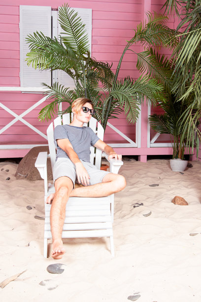 在海上度假。年轻帅气的小伙子在沙滩上拿着冲浪板。图片下载