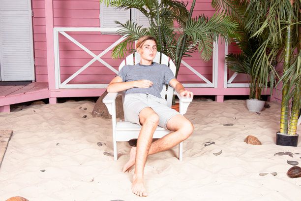 在海上度假。年轻帅气的小伙子在沙滩上拿着冲浪板。图片下载