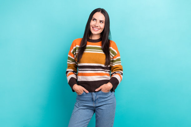 照片正面可爱的微笑女孩穿着条纹橙色毛衣看起来梦幻的空白空间好奇的新闻孤立在蓝色的背景图片下载