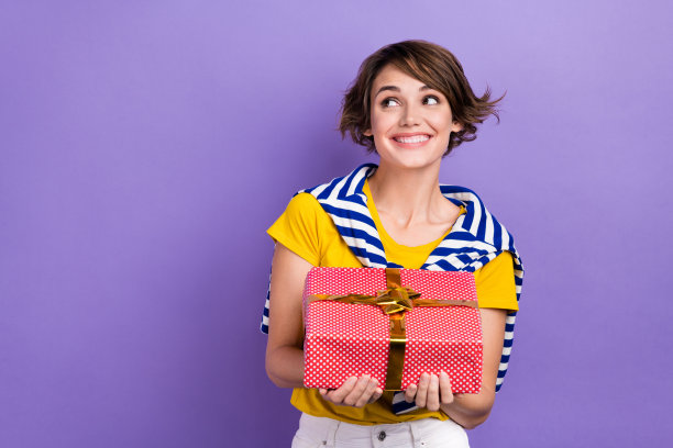 照片可爱漂亮的女士时尚的条纹系套头衫hold礼盒看空空间横幅海报孤立的紫色背景图片下载