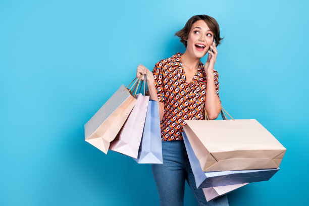 照片甜美梦幻的女士穿着印花衬衫购物者谈论苹果三星设备空白空间孤立的蓝色背景图片下载