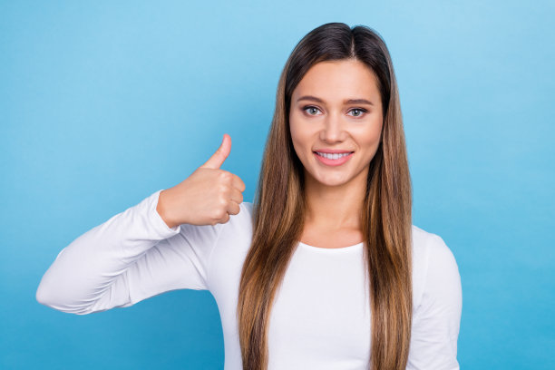 照片正面可爱的女士穿着时尚的衣服，手拇指向上推荐优质的产品，空白的空间孤立在蓝色的背景图片下载