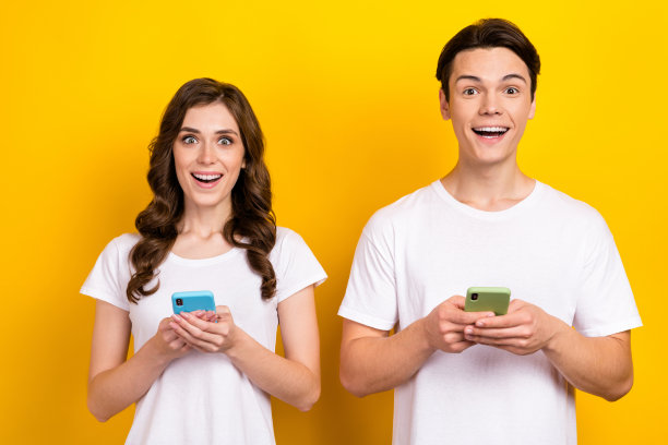 兴奋有趣的新iphone智能手机用户的照片肖像，他们穿着白色t恤，在黄色背景上打字聊天图片下载