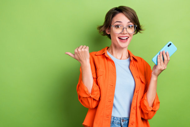 照片中甜美印象深刻的女子穿着牛仔夹克眼镜打字现代设备拇指空白空间孤立绿色背景图片下载