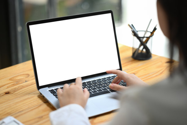 从肩膀上看，一位女商人在木制办公桌上用笔记本电脑工作图片下载