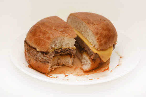 白色背景的芝士汉堡。肉汉堡切成片。图片下载