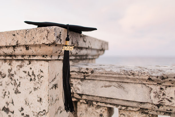 一个黑色毕业帽与黑色流苏2025躺在石墙俯瞰棕榈滩，佛罗里达海岸图片下载