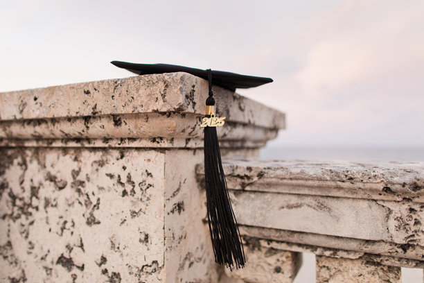 一个黑色毕业帽与黑色流苏2025躺在石墙俯瞰棕榈滩，佛罗里达海岸图片下载