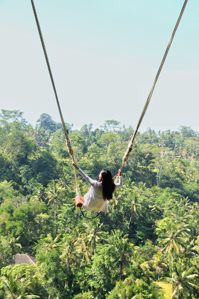 在树林里荡秋千的女人的后视图图片下载