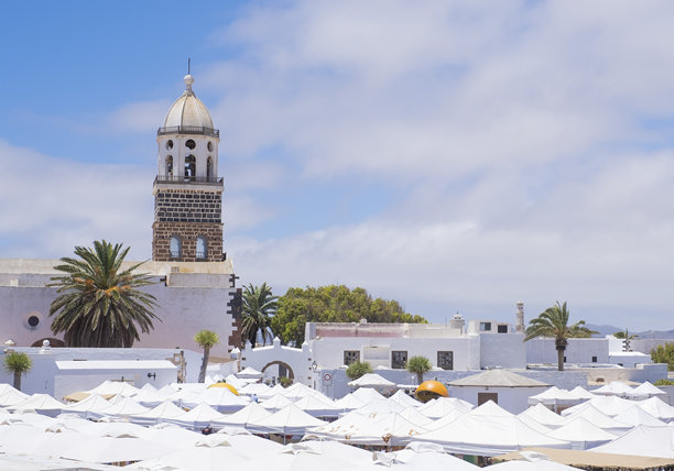 加那利群岛兰萨罗特岛风景如画的白色村庄里，Nuestra Senora de Guadalupe教堂的钟楼，前景是街头市场摊位的屋顶图片下载