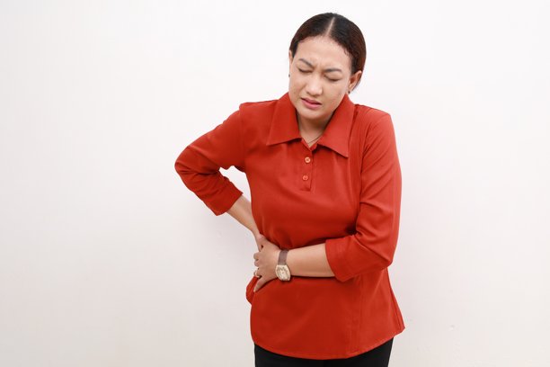 一名亚洲女性右侧胃痛，双手剧烈疼痛。胃痛的概念。隔离在白色背景上图片下载