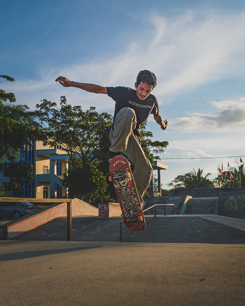 一个年轻人正在用滑板跳跃。图片下载