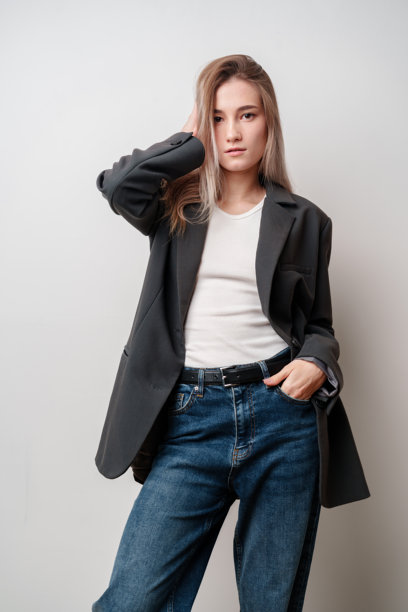 身穿灰色运动上衣和蓝色牛仔裤的年轻女子摆姿势图片下载