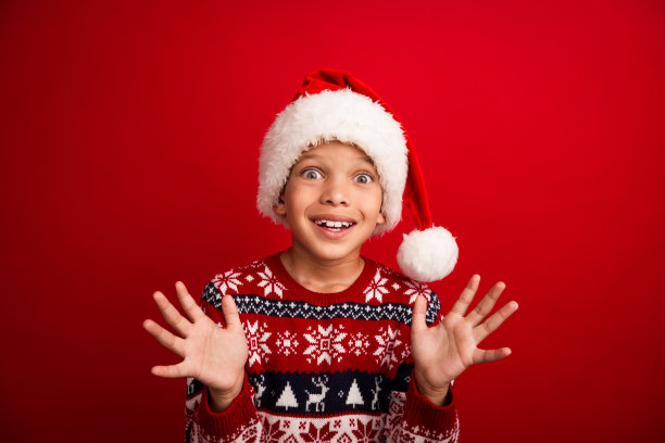 可爱的小男孩的照片肖像兴奋地举起手庆祝圣诞节穿针织衫毛衣孤立的红色背景图片下载