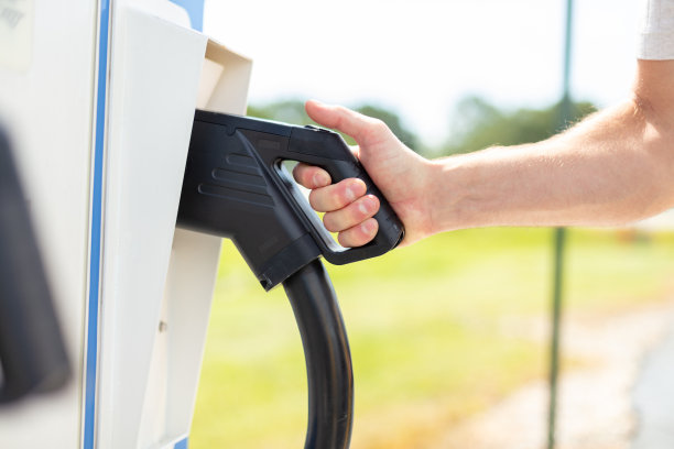 千禧一代男性在美国中西部阳光明媚的早晨照片系列中休息时充电电动汽车图片下载