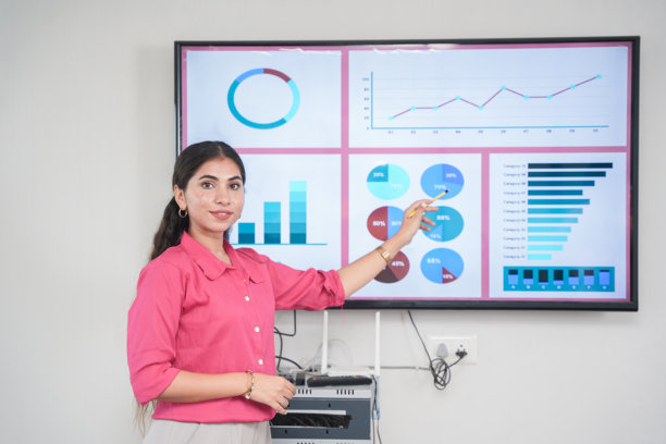 年轻的印度女商人用电视屏幕显示数据、统计数据、图表，向其他员工展示公司的发展情况。销售，收入，分析和战略，创业文化。企业家。图片下载