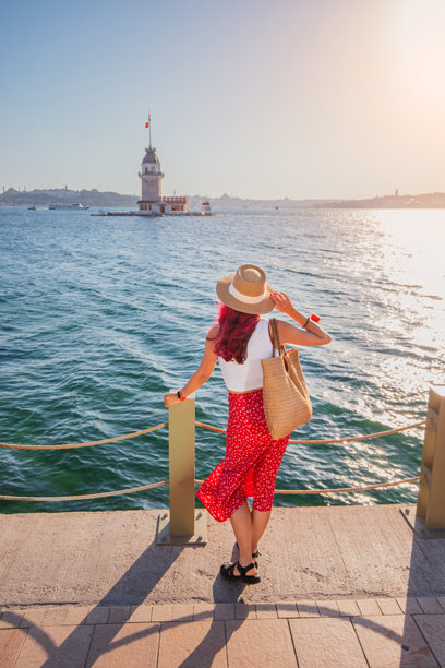 一位旅行者在土耳其享受她的假期，在她的观光冒险中，历史悠久的Kiz Kulesi庄严地站在地平线上。图片下载