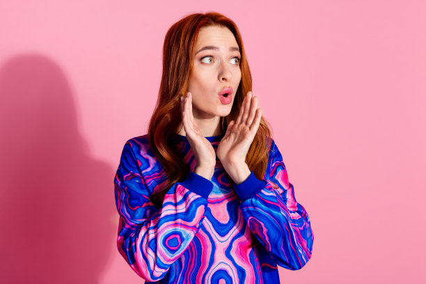 照片中可爱的年轻女子看起来空无一人，穿着套头衫孤立在粉红色的背景上图片下载