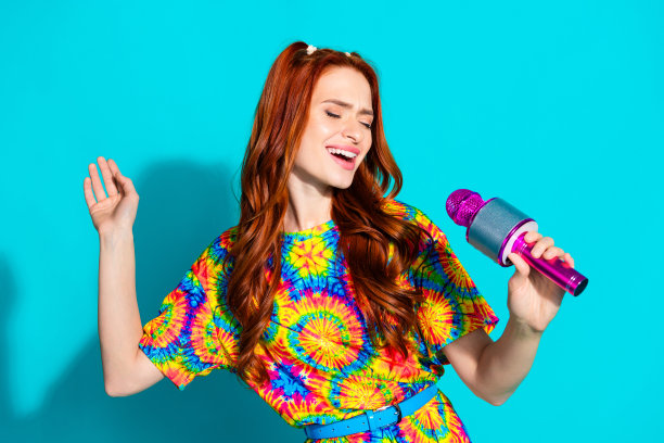 漂亮的年轻女孩唱卡拉ok的照片肖像穿着时髦的彩色服装孤立的海蓝宝石色背景图片下载