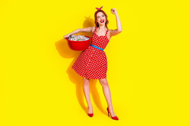 快乐的女士洗衣服整理衣物，在鲜艳的黄色背景中拍摄的照片图片下载