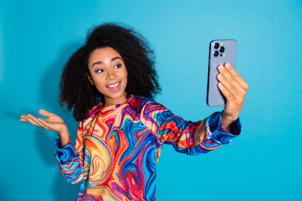 美丽的年轻女孩的照片肖像自拍照片hold显示空穿时髦的彩色服装孤立在蓝色的背景图片下载