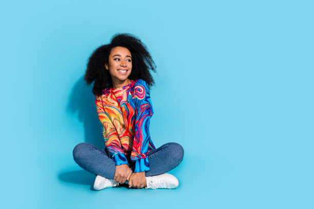 可爱的年轻女士的全身照片坐在地板上看空空间穿着时尚的彩色服装孤立在蓝色的背景图片下载