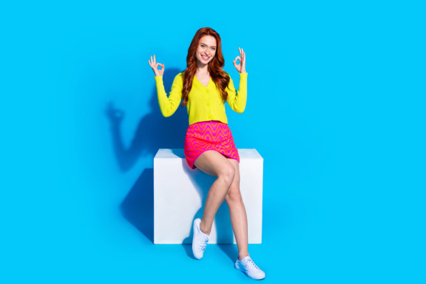 可爱的年轻女士的全身照片坐在立方体好穿着时尚的黄色服装孤立的蓝色背景图片下载