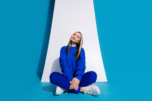 时尚韩国女孩的照片肖像坐在智能手机触摸屏广告数字应用程序隔离在蓝色背景图片下载