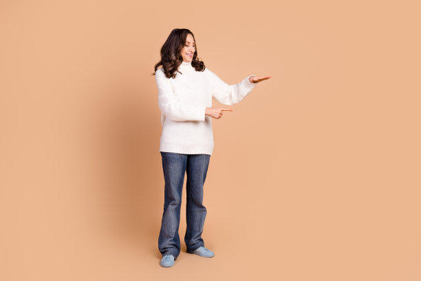 照片中迷人漂亮的美女穿着时尚的衣服，在米色背景上呈现出孤立的空白空间图片下载