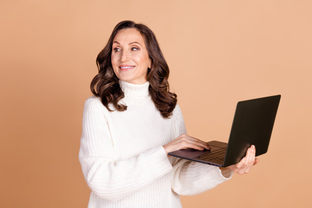 照片中可爱漂亮华丽的高级女子穿着时髦的衣服，用上网本看起来空旷，孤立在米色背景上图片下载