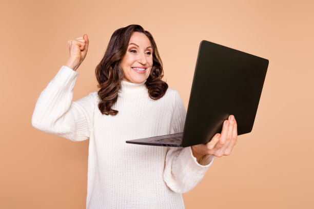 照片中迷人的开朗快乐的女人穿着时髦的衣服，在米色的背景上获得成功图片下载