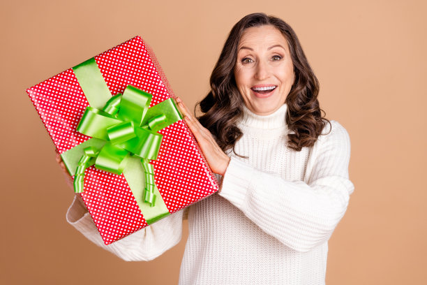 照片中可爱的女人穿着白色时髦的衣服，拿着礼物孤立在米色背景上图片下载