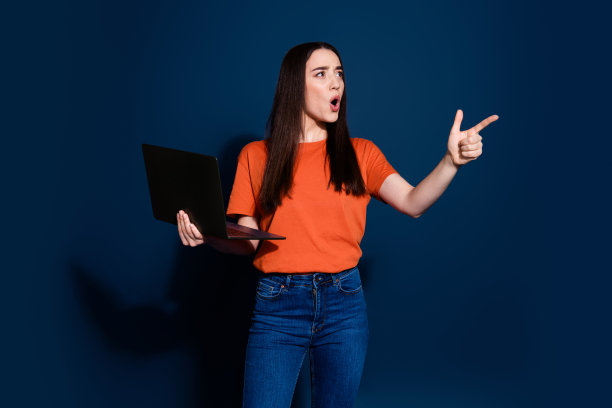 照片中兴奋可爱迷人的女人穿着橙色时髦的衣服，推荐在深蓝色的背景上隔离空的空间图片下载